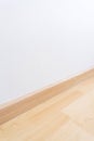 Wooden wall base skirting, finishing material with wood laminate floor and white mortar wall. Empty room with white wall and Royalty Free Stock Photo