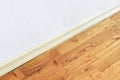 Wooden wall base skirting, finishing material with wood laminate floor and white mortar wall. Empty room with white wall and woode Royalty Free Stock Photo