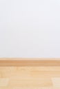 Wooden wall base skirting, finishing material with wood laminate floor and white mortar wall. Empty room with white wall and Royalty Free Stock Photo