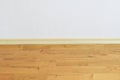 Wooden wall base skirting, finishing material with wood laminate floor and white mortar wall. Empty room with white wall and woode Royalty Free Stock Photo