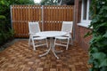 Wooden wall, wooden tiles, two white garden chairs and a round table on  terrace of a residential house Royalty Free Stock Photo