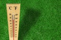 Wooden weather thermometer measurement on a green grass during a hot day