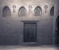 Wooden weathered door, perforated stucco window decorated with floral patterns, and three steps on stone bricks wall