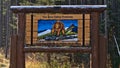 Wooden welcome sign at the northern entrance of popular road Bow Valley Parkway in the Canadian Rocky Mountains with bear.