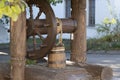 Wooden well in a rural courtyard with a large wheel and old wood pail for water