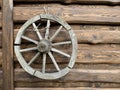 Wooden wheel from an old horse-drawn carriage. The wheel hangs on a wooden fence, as a decoration of the yard. Household items in Royalty Free Stock Photo