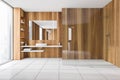 Wooden and white bathroom with sink and glass shower on tiled floor