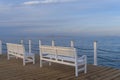 Wooden white benches at the pier with the view of blue sea, cloud beautiful sky Royalty Free Stock Photo