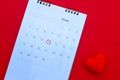 Wooden white calendar with date February 14 and beautiful red hearts on bright red background. Romantic date. Concept Valentine`s