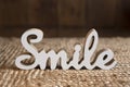 Wooden white figure of the word smile on a woven straw rug