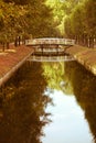 Wooden white footbridge over small water channel river amidst autumn trees with yellow red leaves Royalty Free Stock Photo