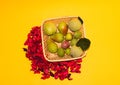 wooden wicker basket with various fruits, yellow background with red autumn decoration, aerial view Royalty Free Stock Photo