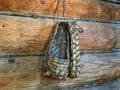 wooden wicker handmade bast shoes or sandals hanging on the wall in the hut