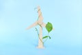 Wooden wind turbine model with fresh green leaves in blue background with copy space. Clean, renewable, sustainable energy.