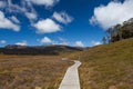 Wooden winding boardwalk in highlands of Cradle Mountain National park on bright sunny day. Tasmania, Australia.