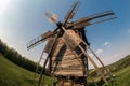 Wooden windmill on the hillside against the backdrop of the rural landscape.