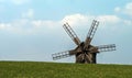 Wooden windmill on the hillside against a background of blue sky