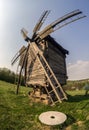 Wooden windmill and millstone on the hillside against the backdrop of the rural landscape. Royalty Free Stock Photo