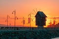 Wooden windmill is symbol and landmark of old town of Nessebar, Bulgaria. Bright orange sunrise in background. Nessebar