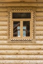 Wooden window with carved plat bands on the wall made of logs Royalty Free Stock Photo