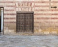 Wooden window with decorated iron grid over stone bricks wall