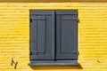 Wooden window with shutters on a yellow, brick facade. Royalty Free Stock Photo