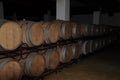 Wooden wine barrels are stored in a wine cellar
