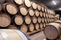 Wooden wine oak barrels stacked in straight rows in order, old cellar of winery, vault. Concept brewery background, professional