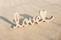 Wooden word love on sandy beach background. Concept of romantic holiday anniversary, proposal, valentines day greeting Royalty Free Stock Photo