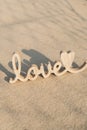 Wooden word love on sandy beach background. Concept of romantic holiday anniversary, proposal, valentines day greeting Royalty Free Stock Photo