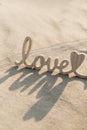 Wooden word love on sandy beach background. Concept of romantic holiday anniversary, proposal, valentines day greeting Royalty Free Stock Photo