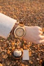 Wooden wristwatch on a girl's arm opposite a background of autumn leaves