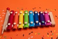 Wooden xylophone in rainbow colors for children an isolated on orange. Paper colorful musical notes surrounding Royalty Free Stock Photo