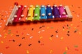 Wooden xylophone in rainbow colors for children an on orange. Paper colorful musical notes surrounding