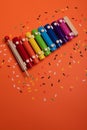 Wooden xylophone in rainbow colors for children an isolated on orange. Paper colorful musical notes surrounding Royalty Free Stock Photo