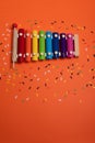 Wooden xylophone in rainbow colors for children an on orange. Paper colorful musical notes surrounding