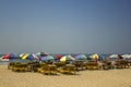 Wooden yellow beach loungers under bright multi-colored sun umbrellas on the sand against the sea under a clear blue sky Royalty Free Stock Photo