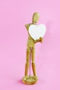 Wooden yellow mannequin holding a white heart in his hands Royalty Free Stock Photo