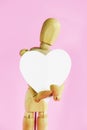Wooden yellow mannequin holding a white heart in his hands Royalty Free Stock Photo