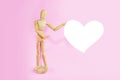 Wooden yellow mannequin holding a white heart in his hands Royalty Free Stock Photo