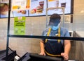 Woodland, CA,USA November 8 2022, Mc Donalds employee using a surgical mask taking an order at the restaurant cashier counter