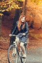 Red haired girl riding on bike in autumnal park Royalty Free Stock Photo