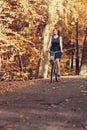 Red haired girl riding on bike in autumnal park Royalty Free Stock Photo