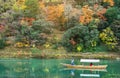 Woods of colorful maple trees on a mountain, a boat on a river beside the forest