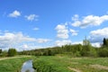 The woods Creek trail, the road. Village. Deciduous trees, young foliage and grass. Cloudy sky