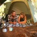 Into the woods. Shot of a young couple lying in a tent looking outwards.