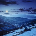 Woodshed on the hillside in winter mountains at night