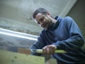 Woodworker with a beard sawing a wooden beam with a hand saw. a carpenter sawing a piece of wood Royalty Free Stock Photo