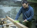 Woodworker with a beard sawing a wooden beam with a hand saw. a carpenter sawing a piece of wood Royalty Free Stock Photo