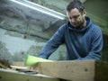 Woodworker with a beard sawing a wooden beam with a hand saw. a carpenter sawing a piece of wood Royalty Free Stock Photo